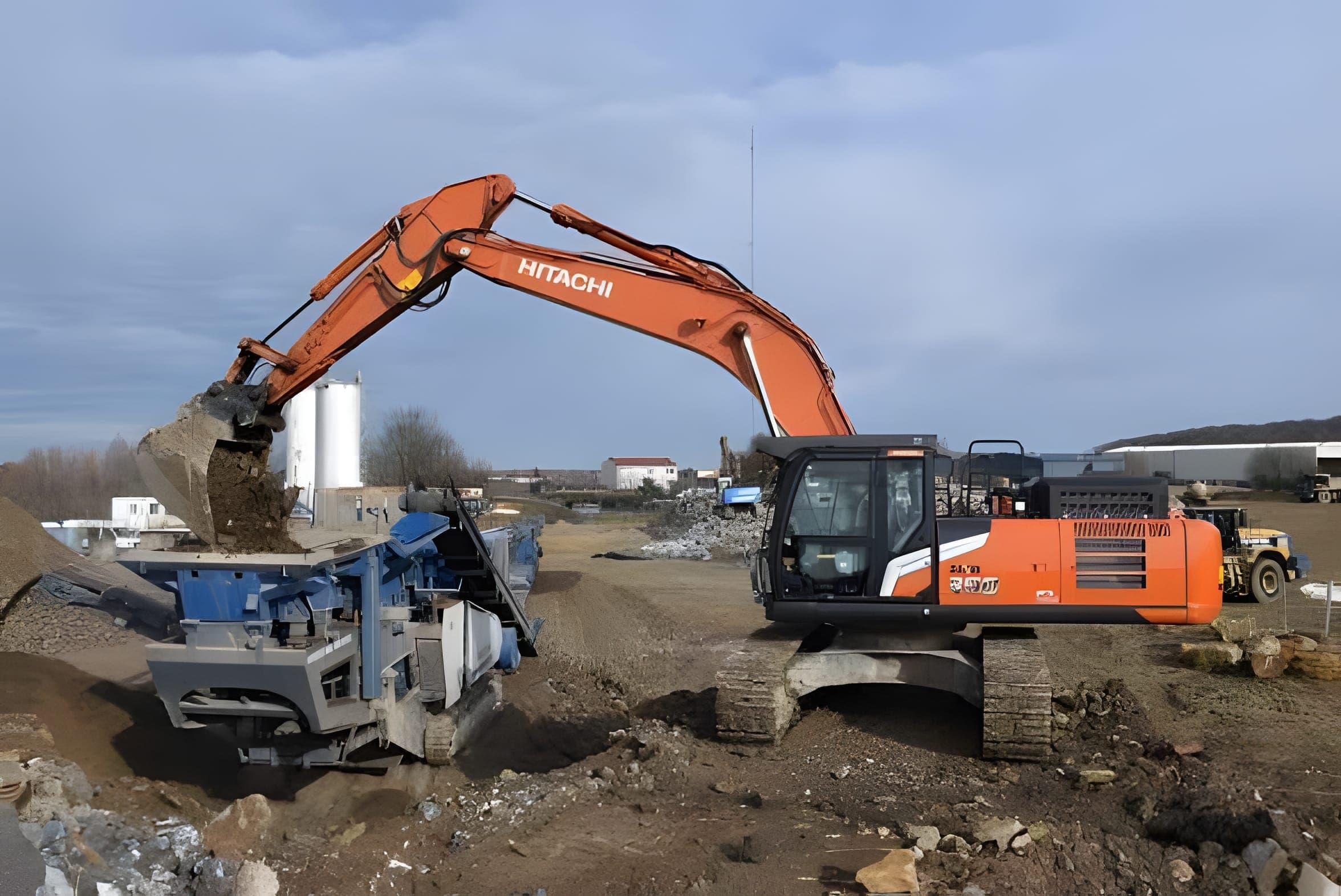 Pelle Hitachi orange alimentant un concasseur mobile