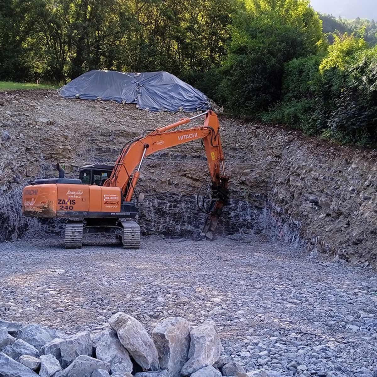 Pelle Hitachi orange en terrassement sur un terrain gravillonné